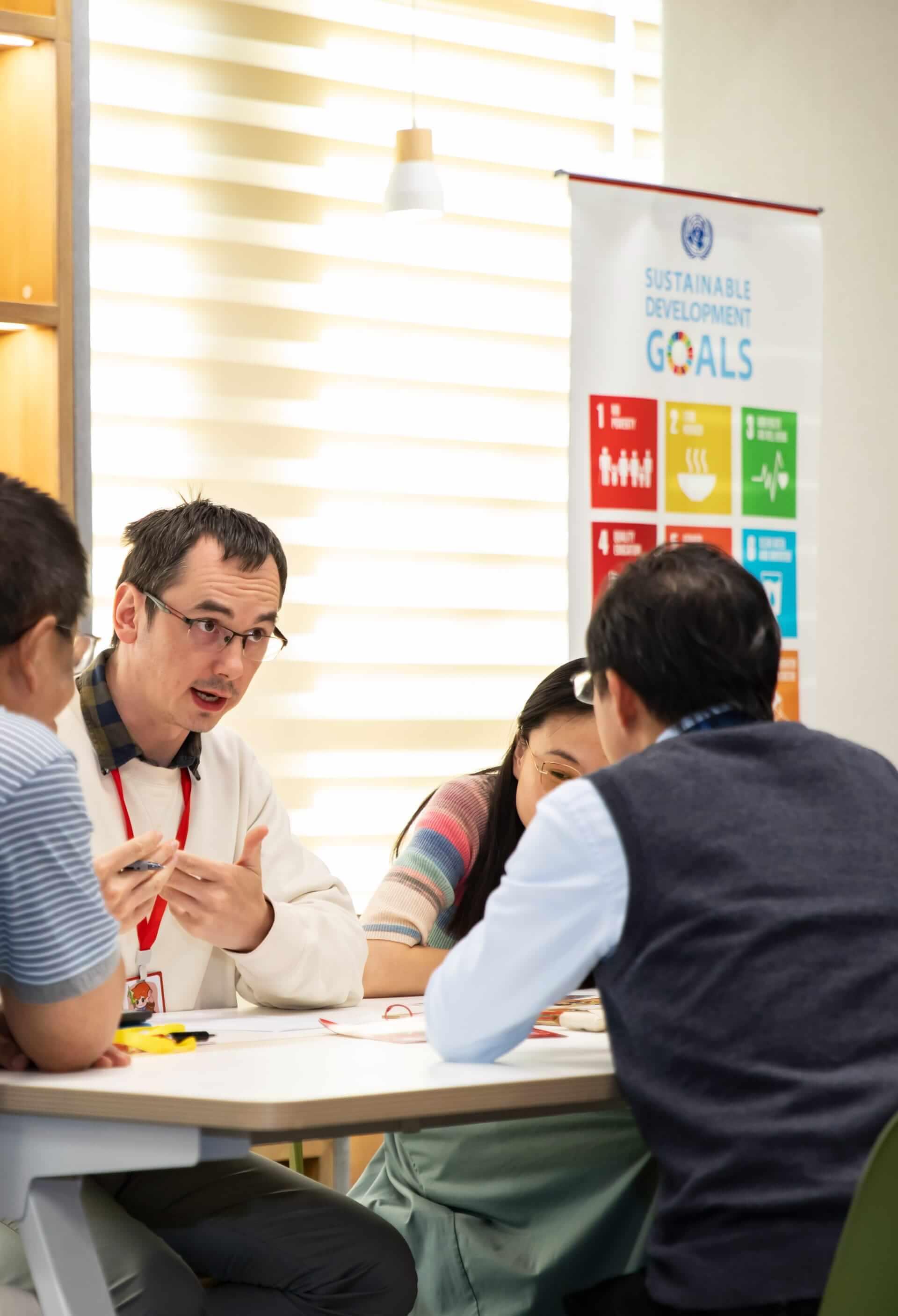 Workshop facilitator discussing SDG materials with partners